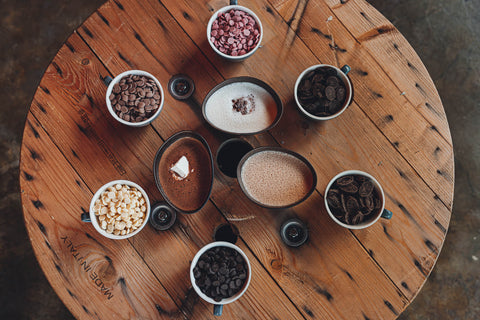 Selection of Kakaw drinks, surrounded by chocolate beans on a rustic wooden table