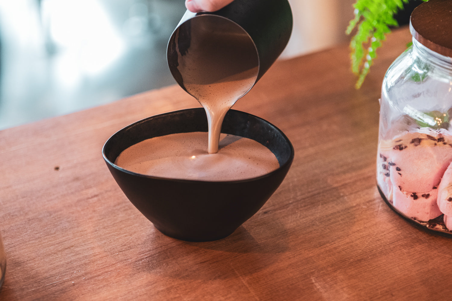 Pouring hot chocolate into a dark bowl