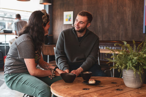 A man and woman sat at a table in Kakaw coffee shop chatting over a hot chocolate